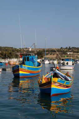 Marsaxlokk, Malta - 11 Ekim 2023: Renkli geleneksel luzzu balıkçı tekneleri güneşli bir sonbahar öğleden sonrasında Malta 'nın tarihi Marsaxlokk limanına yanaştı.