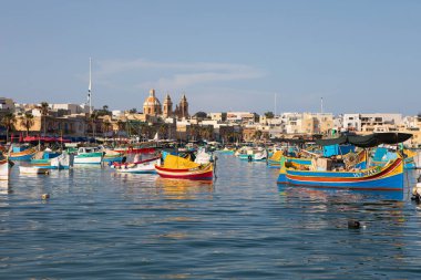 Marsaxlokk, Malta - 11 Ekim 2023: Renkli geleneksel luzzu balıkçı tekneleri güneşli bir sonbahar öğleden sonrasında Malta 'nın tarihi Marsaxlokk limanına yanaştı.