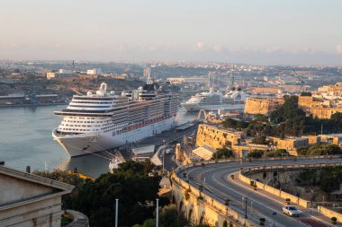 Valletta, Malta - 8 Ekim 2023: MSC Operası da dahil olmak üzere yolcu gemileri, sabahın erken saatlerinde Valletta 'nın Grand Harbour limanına yanaştı. Manzara Malta 'nın tarihi kıyı altyapısı ve artan seyahat turizmine vurgu yapıyor.