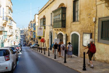 Valletta, Malta - 9 Ekim 2023: Turistler güneşli bir sonbahar gününde 16. yüzyıl Casa Rocca Piccola sarayı yakınlarındaki Eski Fırın Sokağı 'nı keşfediyorlar.