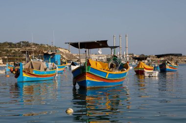 Marsaxlokk, Malta - 11 Ekim 2023: Renkli geleneksel luzzu balıkçı tekneleri güneşli bir sonbahar öğleden sonrasında Malta 'nın tarihi Marsaxlokk limanına yanaştı.