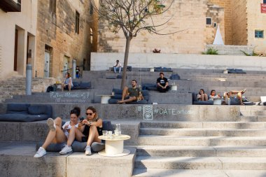 Senglea, Malta - 13 Ekim 2023: İnsanlar Senglea 'daki kafede açık oturmaya dönüştürülen çok katlı basamaklarda rahatlar. 