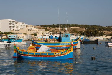Marsaxlokk, Malta - 11 Ekim 2023: Renkli geleneksel luzzu balıkçı tekneleri güneşli bir sonbahar öğleden sonrasında Malta 'nın tarihi Marsaxlokk limanına yanaştı.
