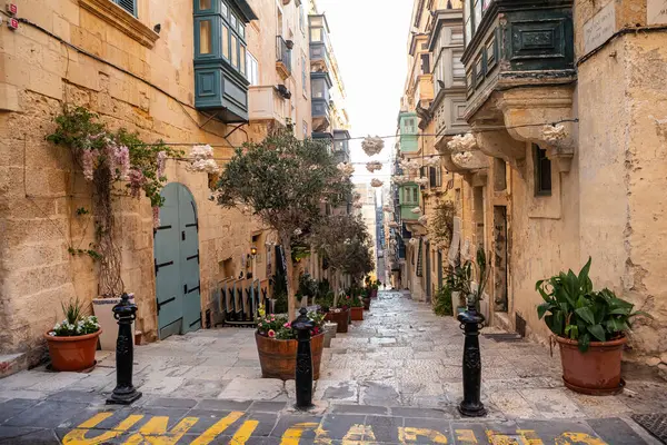 Valletta, Malta - 9 Ekim 2023: Malta 'nın başkenti Valletta' da manzaralı bir cadde, geleneksel kireçtaşı binaları ve renkli Malta balkonlarıyla kaplı.. 