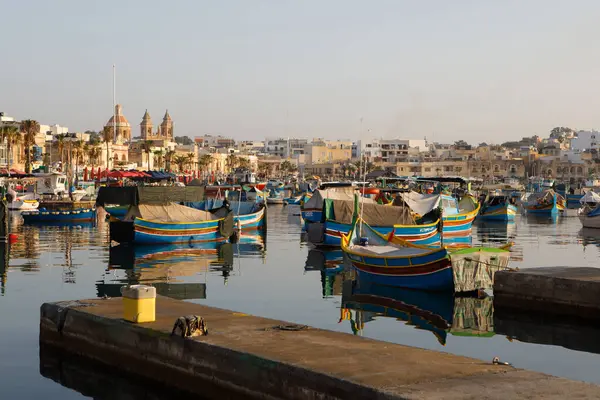 Marsaxlokk, Malta - 12 Ekim 2023: Renkli geleneksel luzzu balıkçı tekneleri güneşli bir sonbahar sabahı Malta 'nın tarihi Marsaxlokk limanına yanaştı. 