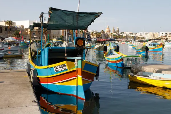 Marsaxlokk, Malta - 11 Ekim 2023: Renkli geleneksel luzzu balıkçı tekneleri güneşli bir sonbahar öğleden sonrasında Malta 'nın tarihi Marsaxlokk limanına yanaştı.