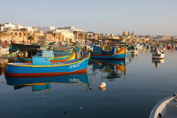 Marsaxlokk, Malta - 12 Ekim 2023: Renkli geleneksel luzzu balıkçı tekneleri güneşli bir sonbahar sabahı Malta 'nın tarihi Marsaxlokk limanına yanaştı.