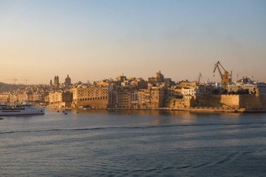 Valletta, Malta - 9 Ekim 2023: Valletta 'nın tarihi silueti, antik takviyeler ve modern liman vinçlerinin yer aldığı Grand Harbour boyunca uzanır..