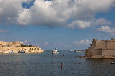 Valletta, Malta - 13 Ekim 2023 Grand Harbour 'dan tarihi Fort Ricasoli ve Valletta şehrinden büyük lüks bir yat denize açılıyor..