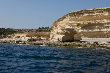Aziz Peter Havuzu 'nun engebeli, dokulu kireçtaşı kıyı şeridi uçsuz bucaksız gökyüzünün altında açık mavi Akdeniz ile buluşur, Malta