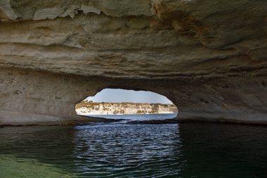 Aziz Peter Havuzu 'nun doğal kemeri Akdeniz turkuazını ve uzak uçurumları çerçeveler.