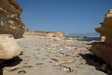 Aziz Peter Havuzu 'nun engebeli, dokulu kireçtaşı kıyı şeridi uçsuz bucaksız gökyüzünün altında açık mavi Akdeniz ile buluşur, Malta