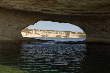 Aziz Peter Havuzu 'nun doğal kemeri Akdeniz turkuazını ve uzak uçurumları çerçeveler.