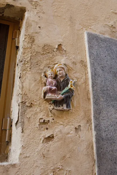 Aziz Anthony 'nin Bebek İsa' yı tutarken seramik bir rahatlama Rabat, Malta 'da soyulmuş, yıpranmış bir duvara gömülü.