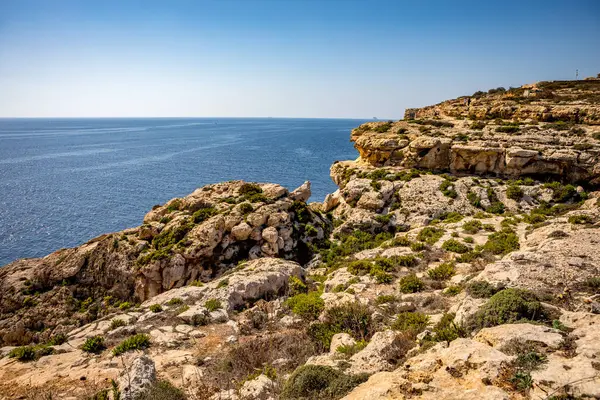 Akdeniz 'in berrak mavi ve turkuaz sularına, Birzebbuga, Malta' da parlak bir gökyüzü altında dramatik kireçtaşı kayalıkları düşüyor.