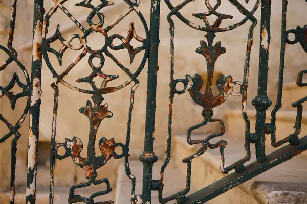 Isla, Malta 'da çürüyen, süslü, karmaşık desenler, pas ve yeşil boya içeren demir parmaklıkların yakın çekimi.