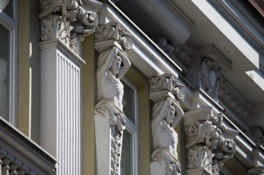 Mimari destek ve dekoratif unsurlar olarak hizmet veren zarif süvari figürler Litvanya 'nın Vilnius kentindeki Didzioji Caddesi' ndeki bir binanın süsleme cephesini süslüyor.