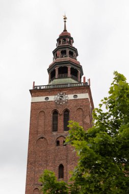 Lidzbark Warminski 'deki tarihi bir kilisenin etkileyici kırmızı tuğla kulesinde süslü bir saat yüzü ve yemyeşil bir kule bulunur.
