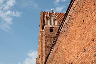 Polonya 'nın Warmia-Masuria kentindeki Olsztyn Kalesi' nin etkileyici Gotik geçidi mavi gökyüzüne karşı tarihi tuğla ve mimari detaylar sergiliyor.