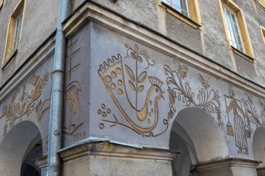 Olsztyn, Polonya - 21 Haziran 2025: Kuşların ve çiçeklerin resmedildiği geleneksel sgraffito halk sanatı Olsztyn 'in Eski Kasabası' ndaki tarihi bir binanın cephesini süslüyor.