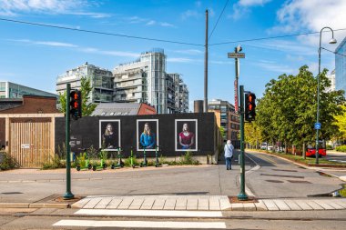 Oslo, Norveç - 15 Temmuz 2025: Arka planda modern mimari, scooterlar ve kentsel trafik ışıkları ile Dokkveien yakınlarındaki siyah bir duvarda sokak resimleri sergilendi.