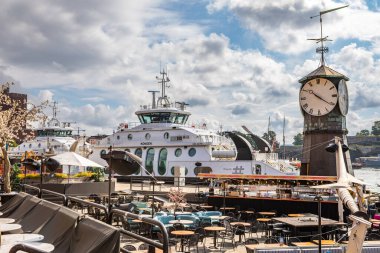 Oslo, Norveç - 15 Temmuz 2025: Feribot Aker Brygge limanındaki tarihi saat kulesinin yakınına yanaştı..
