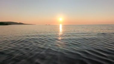 Michigan 'daki Superior Gölü' nün üzerinde gün batımı ve arka planda Kirpi Dağları.