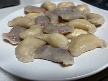 Bu resim beyaz bir tabakta servis edilen geleneksel bir Ukrayna Varenyky (hamur köftesi) tabağını gösteriyor. Varenyky yumuşak ve taze pişmiş görünür, parlak bir dış görünüşü ile, onlar kaynatılmış olduğunu gösterir.