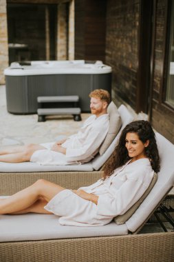 Handsome young couple relaxing on beds on the outdoor terrace