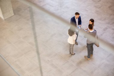 Genç iş adamlarının hava görüntüsü ofis koridorunda tartışılıyor.