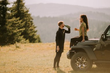 Handsome young couple relaxing on a terrain vehicle hood at countryside