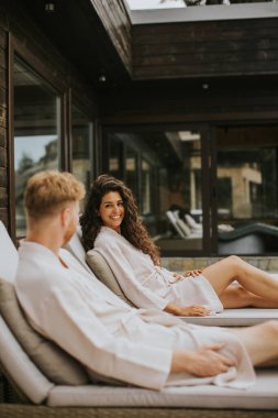 Handsome young couple relaxing on beds on the outdoor terrace