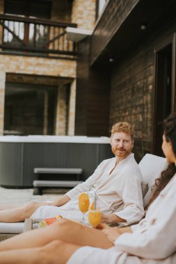 Yakışıklı genç çift yataklarında dinleniyor ve terasta taze portakal suyu içiyor.