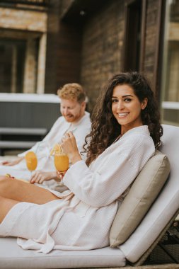 Yakışıklı genç çift yataklarında dinleniyor ve terasta taze portakal suyu içiyor.