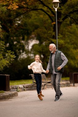 Yakışıklı büyükbaba sonbahar günü torunuyla parkta vakit geçiriyor.