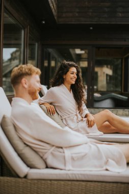 Handsome young couple relaxing on beds on the outdoor terrace