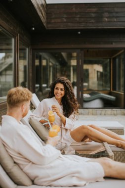 Yakışıklı genç çift yataklarında dinleniyor ve terasta taze portakal suyu içiyor.
