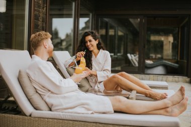 Yakışıklı genç çift yataklarında dinleniyor ve terasta taze portakal suyu içiyor.
