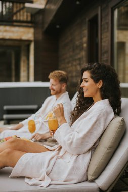 Yakışıklı genç çift yataklarında dinleniyor ve terasta taze portakal suyu içiyor.