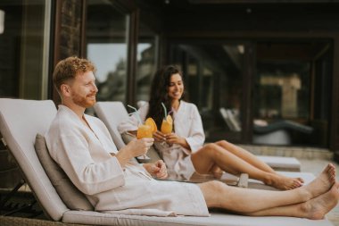 Yakışıklı genç çift yataklarında dinleniyor ve terasta taze portakal suyu içiyor.
