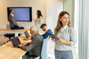 Takım lideri olarak meslektaşlarının önünde dijital tablet ile başlangıç ofisinde Pretty genç iş kadını