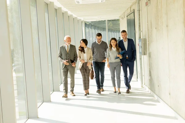 stock image Group of corporate business professionals walking through office corridor on a sunny day