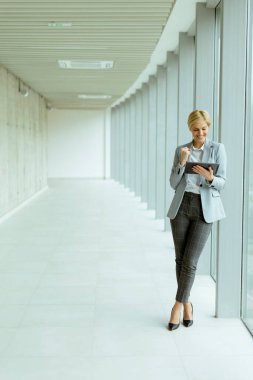 Modern ofis koridorunda dijital tablet kullanan iş kadını