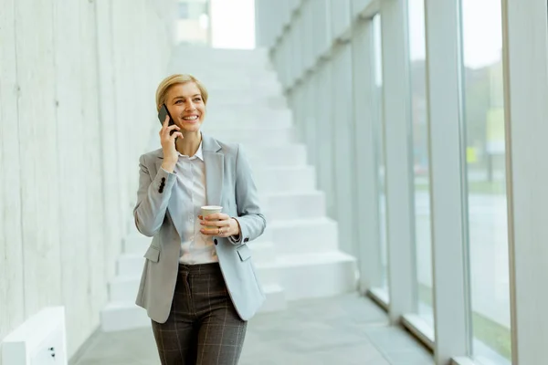 Affärskvinna Som Använder Mobiltelefon När Han Går Den Moderna Kontorshallen — Stockfoto