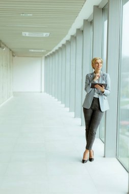 Modern ofis koridorunda dijital tablet kullanan iş kadını