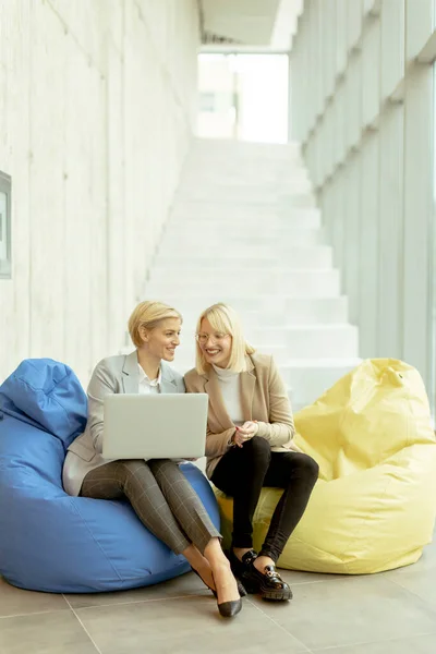 stock image Two businesswomen working on laptop on lazy bags in the modern office