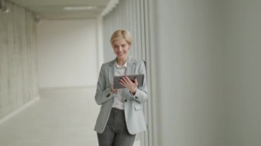 Modern ofis koridorunda dijital tabletli iş kadını