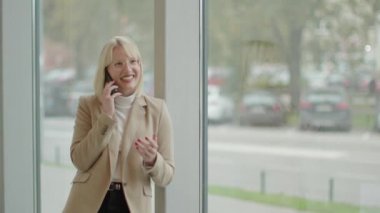 Modern ofis koridorunda cep telefonu kullanan bir iş kadını.