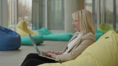 Modern ofiste iş kadını laptopta tembel çanta üzerinde çalışıyor.