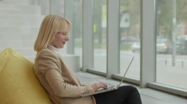 Modern ofiste iş kadını laptopta tembel çanta üzerinde çalışıyor.
